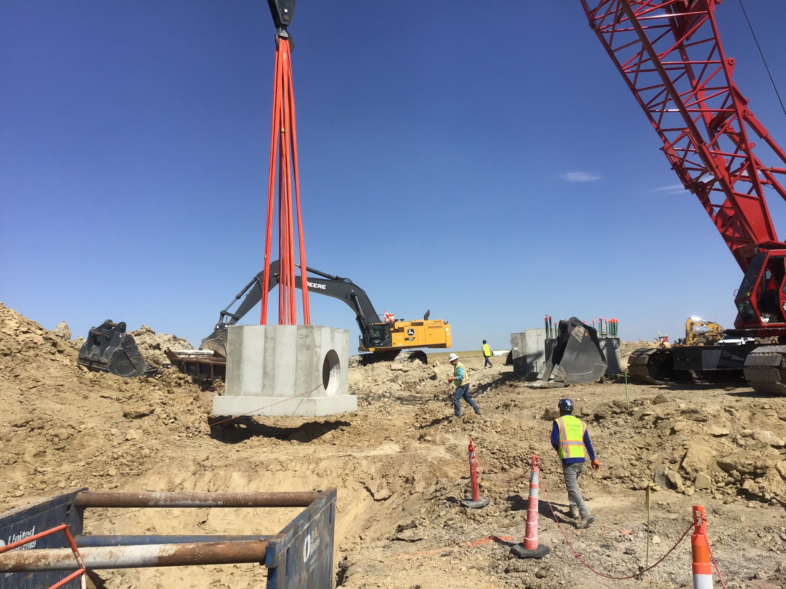 Crane lifting large precast concrete drainage structure into excavation