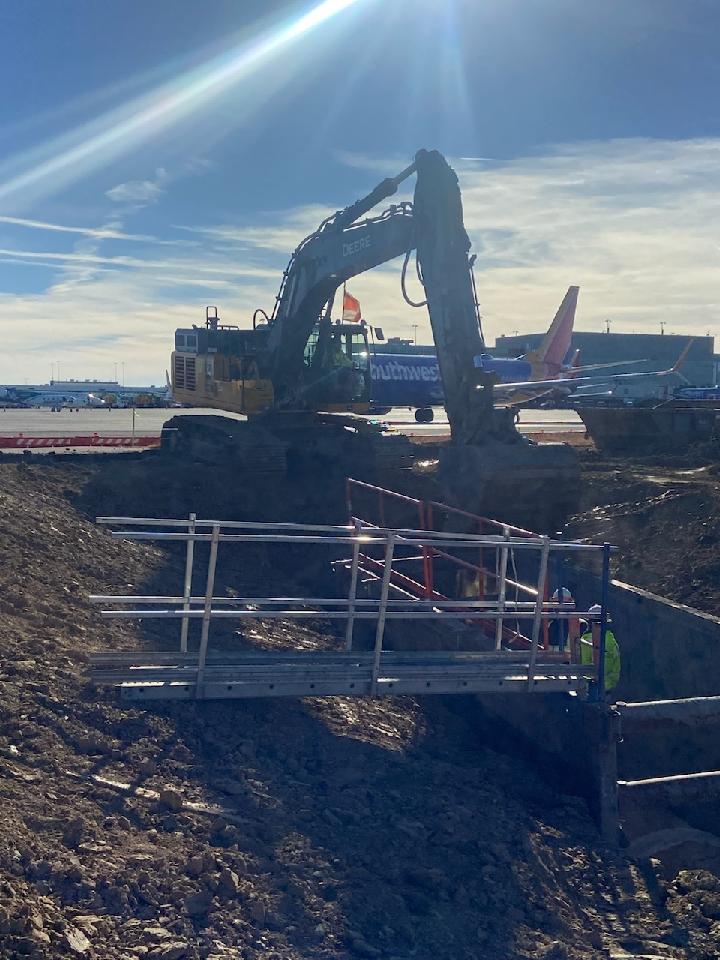 Excavator working near airplane on airport runway