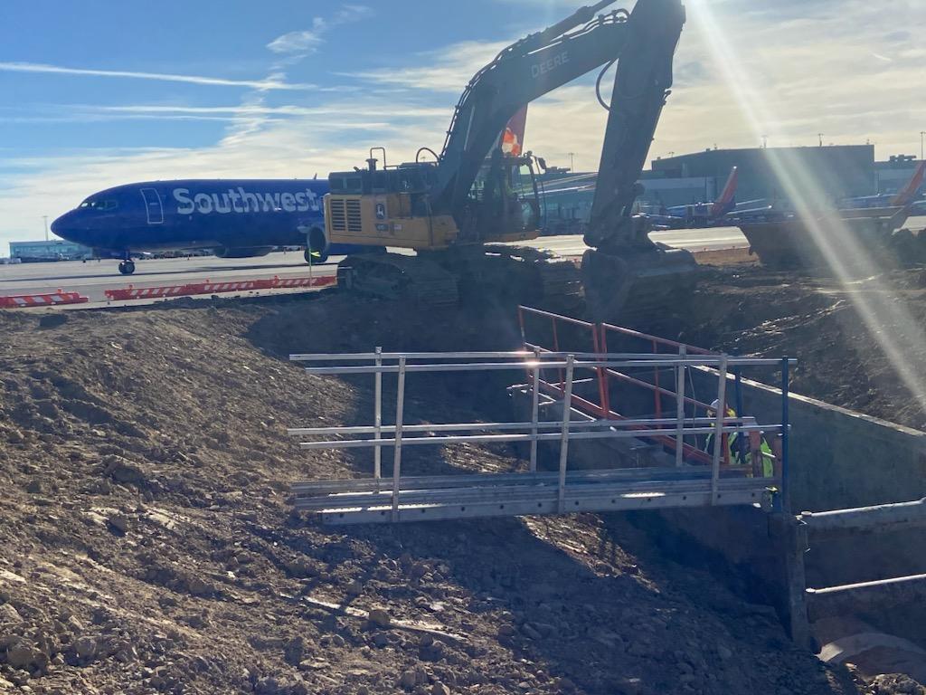 Excavator working near airplane on airport runway