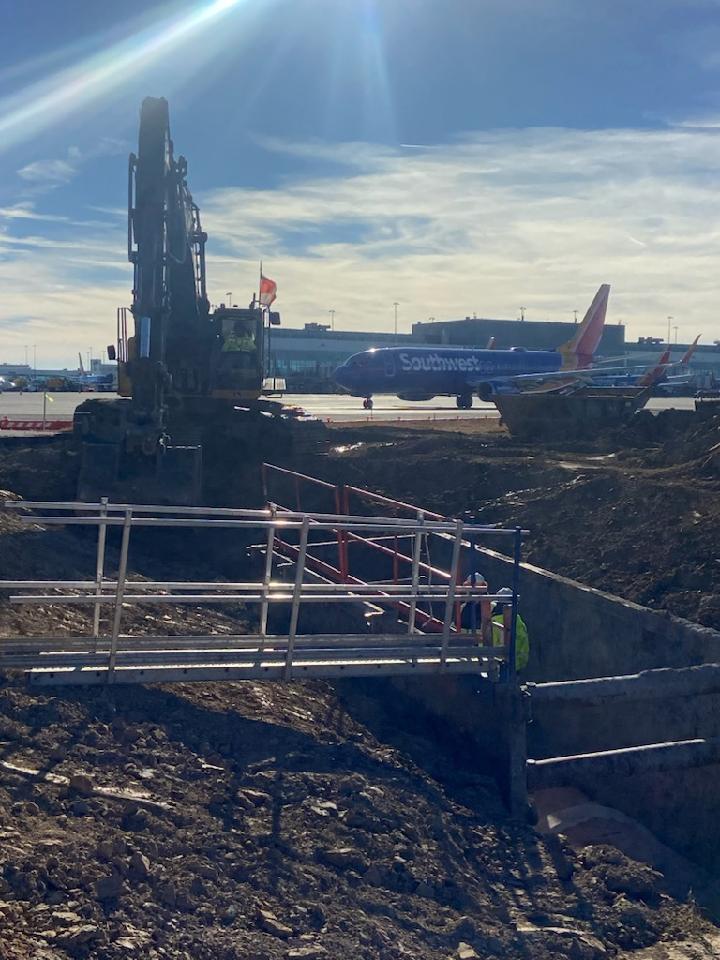 Excavator working near airplane on airport runway
