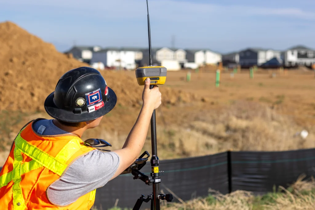 Surveyor using GNSS equipment on a heavy civil construction site during grading work.